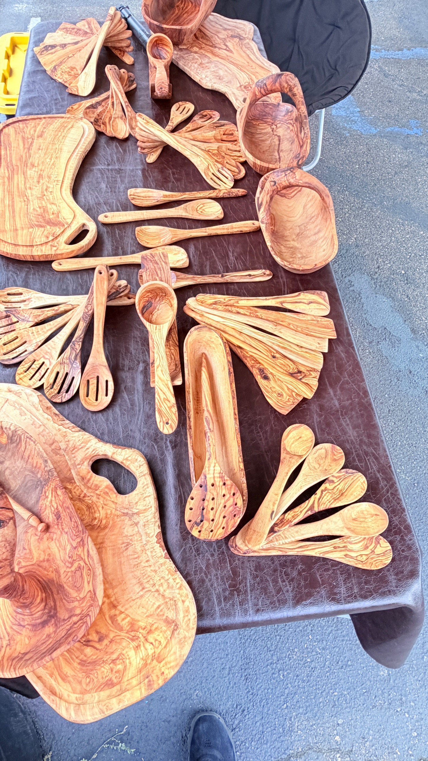 Hand carved olive wood serving spoons and cups arranged on dark cloth